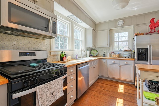 kitchen with a wealth of natural light, wooden counters, stainless steel appliances, and a sink