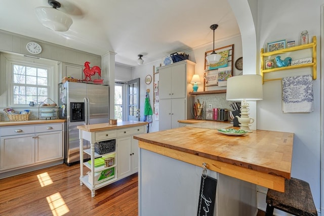 kitchen with wood finished floors, open shelves, wood counters, decorative light fixtures, and stainless steel fridge