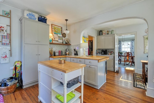 kitchen featuring arched walkways, wooden counters, and open shelves