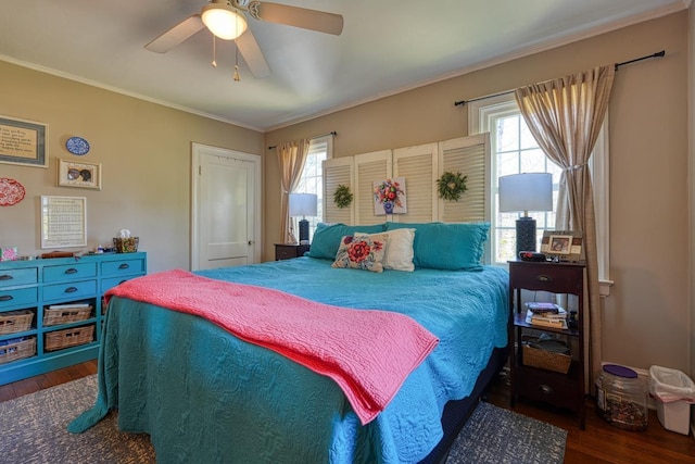 bedroom with ceiling fan, wood finished floors, and crown molding