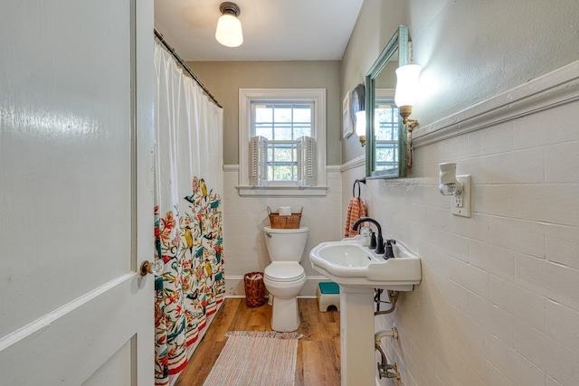 full bathroom with a wainscoted wall, toilet, a shower with curtain, wood finished floors, and tile walls