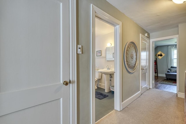 corridor featuring baseboards and light carpet