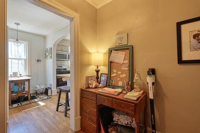 office area featuring wood finished floors, arched walkways, and ornamental molding