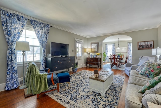 living room featuring wood finished floors, arched walkways, and a wealth of natural light