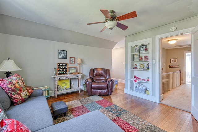 living room featuring hardwood / wood-style flooring, built in features, a ceiling fan, and vaulted ceiling