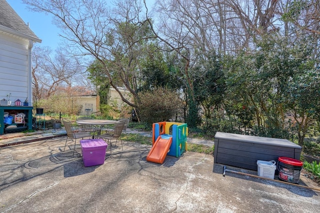 view of playground featuring a patio and outdoor dining area