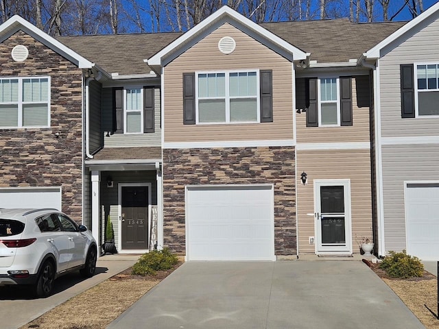 view of property featuring a garage, stone siding, roof with shingles, and concrete driveway