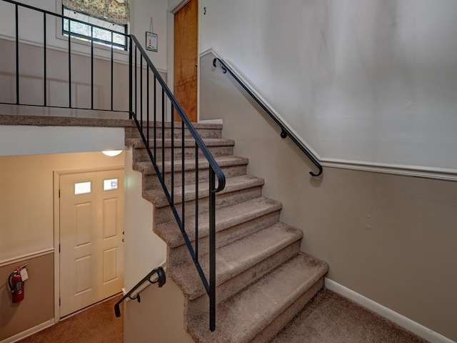 staircase featuring baseboards and carpet floors