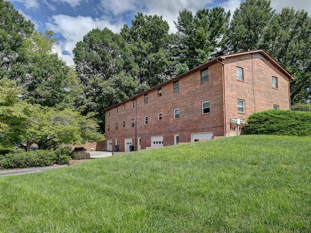 view of property exterior with an attached garage, brick siding, and a yard