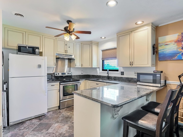 kitchen with under cabinet range hood, cream cabinets, stainless steel appliances, and a sink