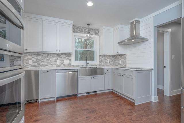 kitchen featuring backsplash, wall chimney range hood, dark wood finished floors, light countertops, and stainless steel appliances