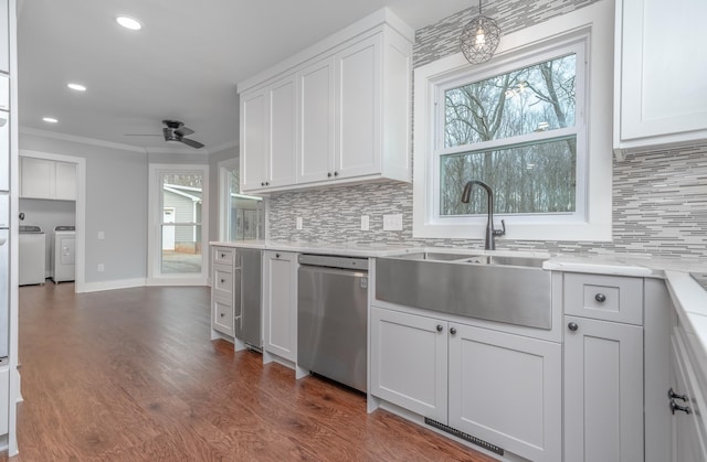 kitchen featuring washer and clothes dryer, a sink, stainless steel dishwasher, dark wood finished floors, and crown molding