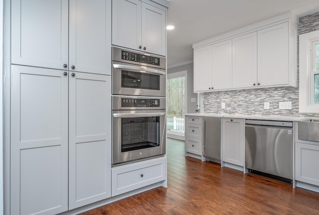 kitchen featuring stainless steel appliances, dark wood-style floors, decorative backsplash, and crown molding