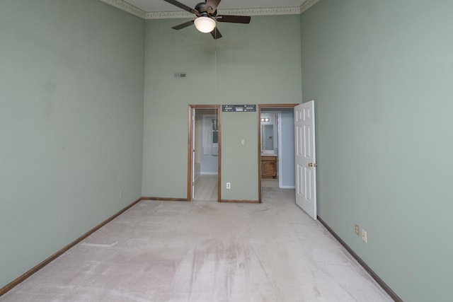 unfurnished bedroom featuring visible vents, connected bathroom, a high ceiling, carpet flooring, and baseboards