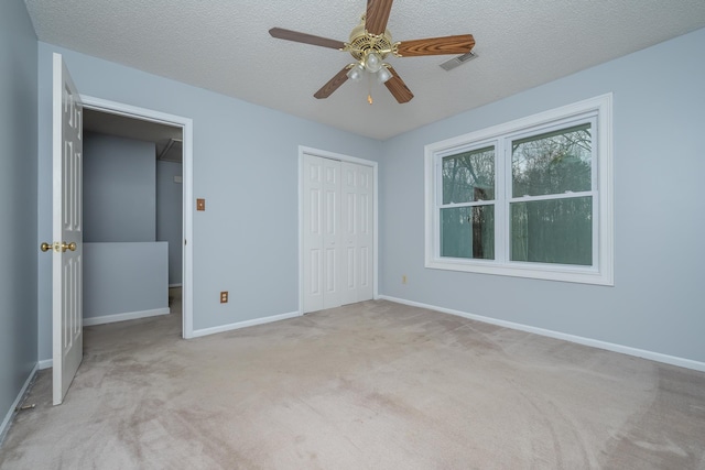 unfurnished bedroom featuring baseboards, visible vents, carpet floors, a closet, and a textured ceiling