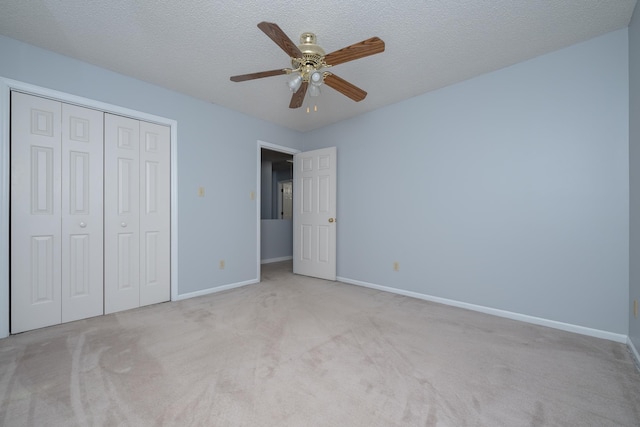 unfurnished bedroom featuring a closet, carpet flooring, a textured ceiling, and baseboards