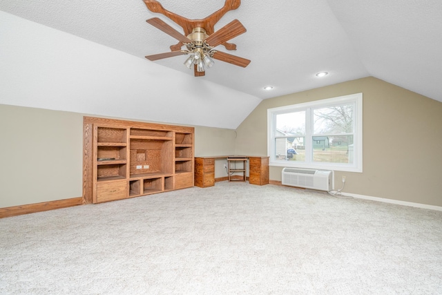 additional living space with a textured ceiling, lofted ceiling, baseboards, and a wall mounted AC