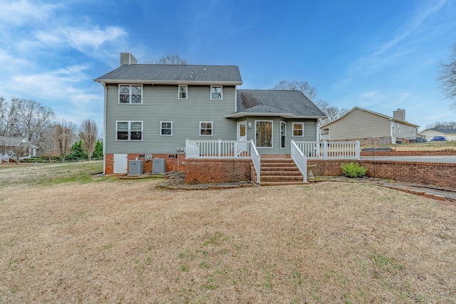 back of property featuring a lawn, central AC, a chimney, and a shingled roof