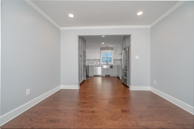 unfurnished living room featuring a sink, baseboards, dark wood-type flooring, and crown molding