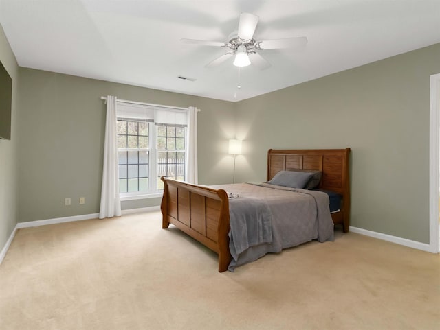 bedroom with visible vents, light colored carpet, baseboards, and ceiling fan