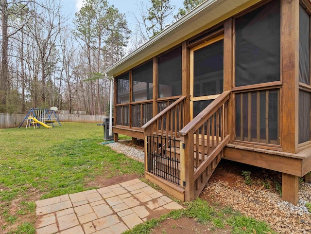 view of yard featuring a playground, fence, and a sunroom