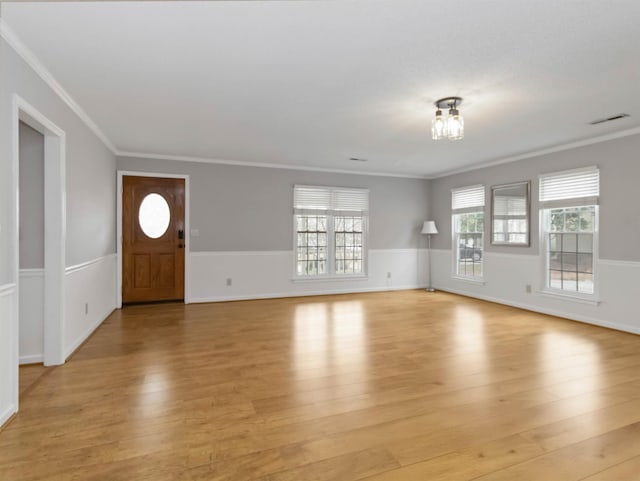 unfurnished living room featuring light wood-style flooring, wainscoting, visible vents, and ornamental molding