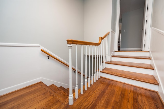 staircase featuring baseboards and wood finished floors