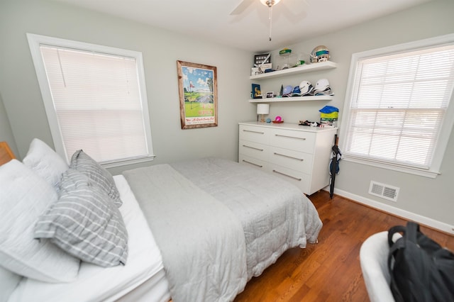 bedroom with visible vents, a ceiling fan, baseboards, and wood finished floors