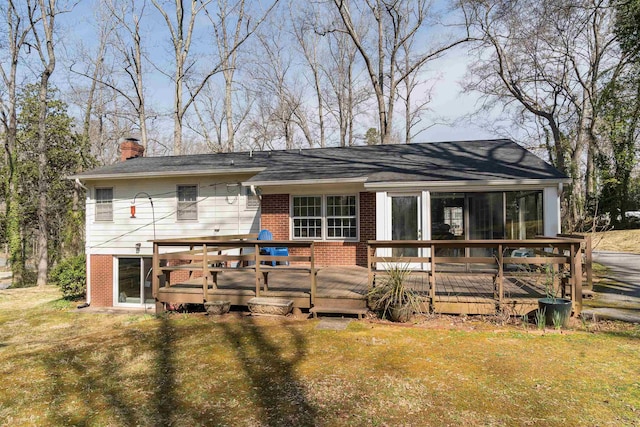 back of house featuring a deck, a yard, brick siding, and a chimney