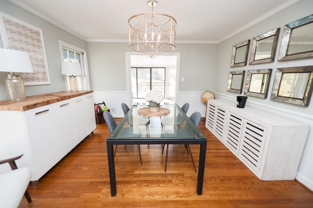 dining space featuring wainscoting, a notable chandelier, light wood-style flooring, and ornamental molding