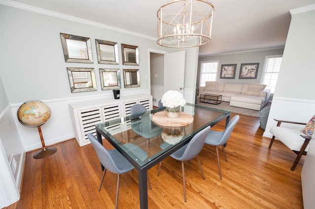 dining space with ornamental molding, wood finished floors, baseboards, and a chandelier