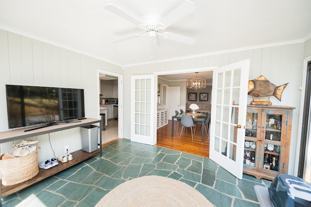 living room featuring dark wood finished floors, ceiling fan with notable chandelier, french doors, and ornamental molding