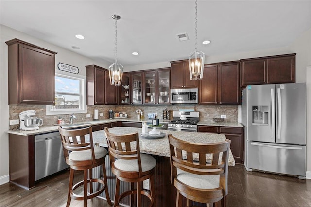 kitchen with dark brown cabinets, visible vents, tasteful backsplash, and appliances with stainless steel finishes