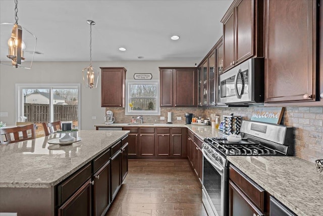 kitchen featuring light stone counters, backsplash, appliances with stainless steel finishes, and a wealth of natural light