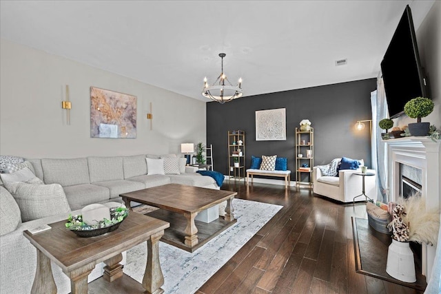 living area featuring a fireplace, an inviting chandelier, dark wood-style floors, and visible vents