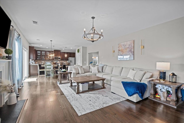 living area with visible vents, recessed lighting, an inviting chandelier, and hardwood / wood-style flooring