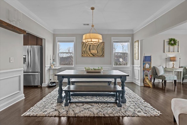 dining room with visible vents, dark wood-style floors, a decorative wall, wainscoting, and crown molding