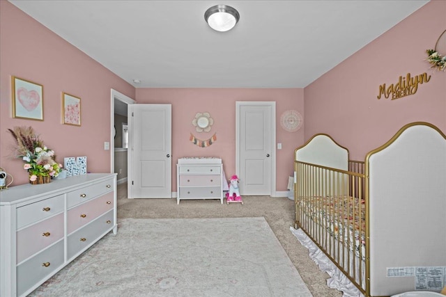 carpeted bedroom featuring a crib and baseboards