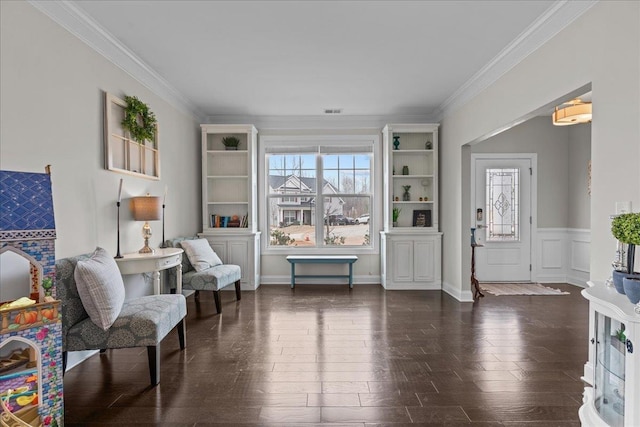 living area with dark wood-style floors, visible vents, wainscoting, and crown molding