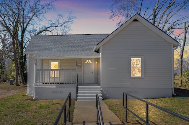 view of front of home featuring crawl space, covered porch, roof with shingles, and a front yard