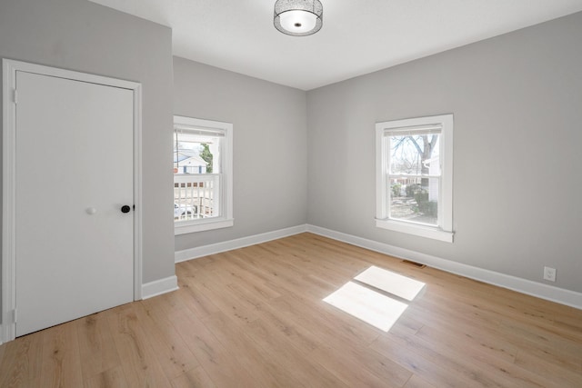 empty room featuring visible vents, a healthy amount of sunlight, baseboards, and light wood-style floors