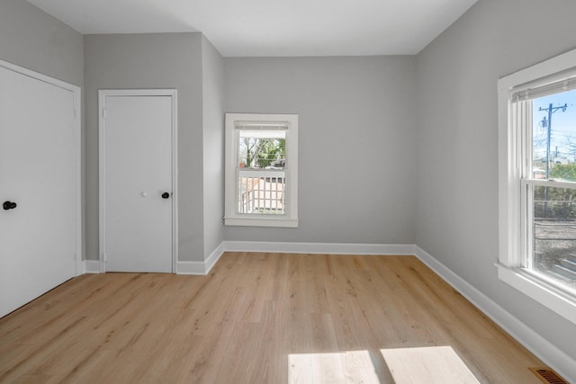 spare room with light wood-style flooring, plenty of natural light, baseboards, and visible vents