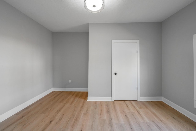 spare room with baseboards and light wood finished floors