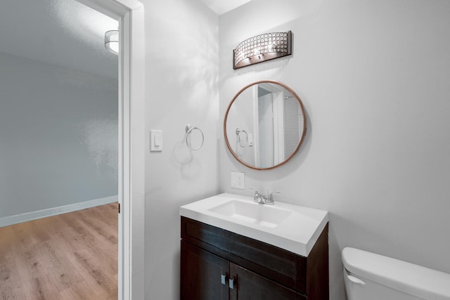 bathroom with toilet, vanity, baseboards, and wood finished floors