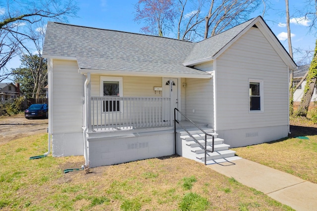 view of front of home featuring crawl space, covered porch, a shingled roof, and a front lawn