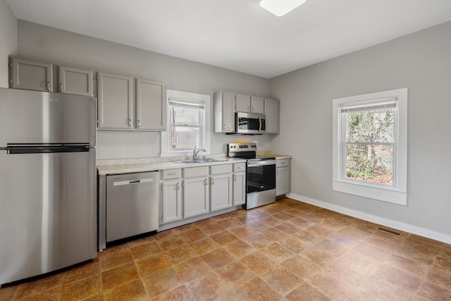 kitchen featuring visible vents, a sink, stainless steel appliances, light countertops, and baseboards