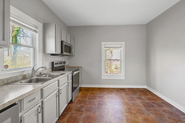 kitchen featuring a sink, stainless steel appliances, baseboards, and light countertops