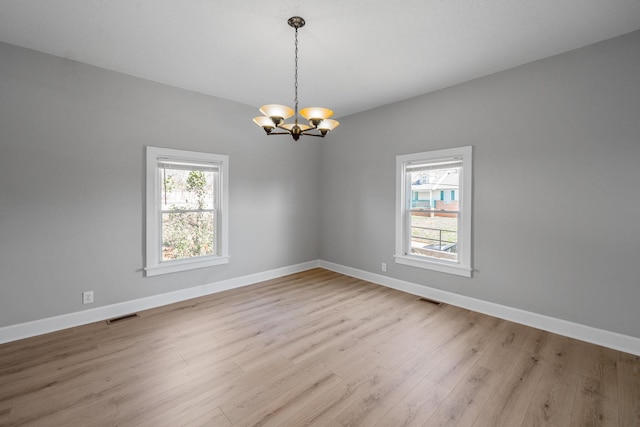 empty room featuring visible vents, a notable chandelier, and a healthy amount of sunlight