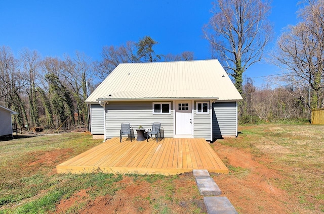 rear view of house featuring metal roof, a lawn, and a wooden deck