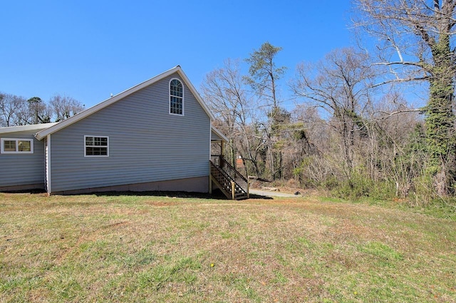 view of side of property with stairway and a lawn